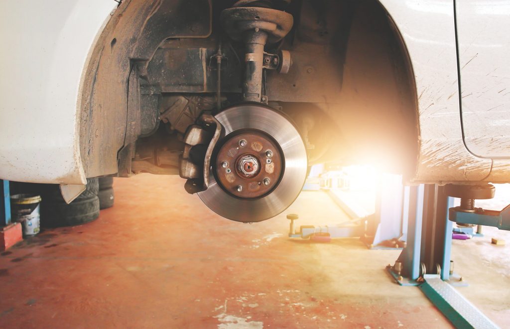 Disc brakes and calipers that remove the wheels of a car in the auto repair garage with sunlight.